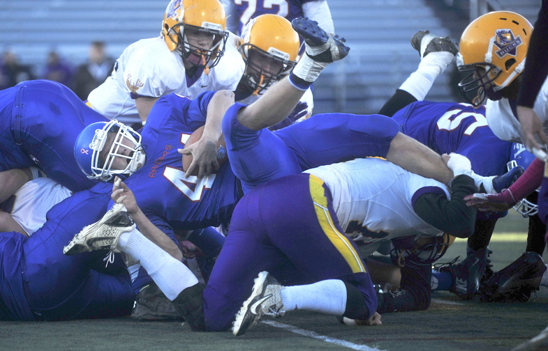 CLASS D FOOTBALL:Oak Hill High School’s Kyle Flaherty, 44, dives over the pile of Bucksport High School defenders for a second quarter touchdown in the Class D state championship game at Fitzpatrick Stadium in Portland on Saturday.
