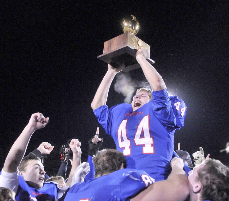 CLASS D FOOTBALL:Oak Hill High School’s Kyle Flaherty, 44, hoists the championship trophy over his head as his teammates put him on their shoulders after defeating Bucksport High School 42-35 in the Class D state championship game at Fitzpatrick Stadium in Portland on Saturday.