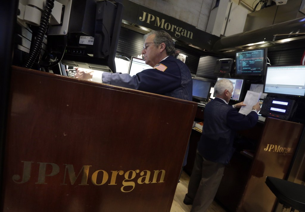 A pair of traders work in the JPMorgan booth on the floor of the New York Stock Exchange on Tuesday. The $13 billion settlement amount is only about half of JPMorgan’s record 2012 net income of $21.3 billion, which made it one of the most profitable U.S. banks last year.