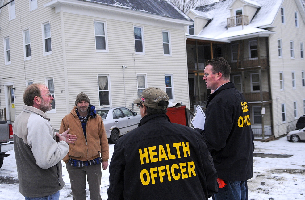 INSPECTION: Property maintenance manager Jim Dutil speaks with city and state officials Tuesday after an inspection of the apartment building at 37 Washington St. in Augusta, owned by Jim Pepin. The city of Augusta got an administrative search warrant last week to enter and inspect several of Pepin’s multi-unit properties.