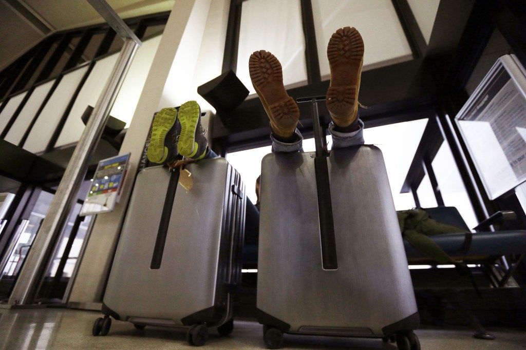 A couple rest their feet on their luggage while waiting for their flight to return home to Germany at Newark Liberty International Airport on Wednesday in Newark, N.J. East Coast travel delays didn’t cause a major ripple effect for the rest of the nation.