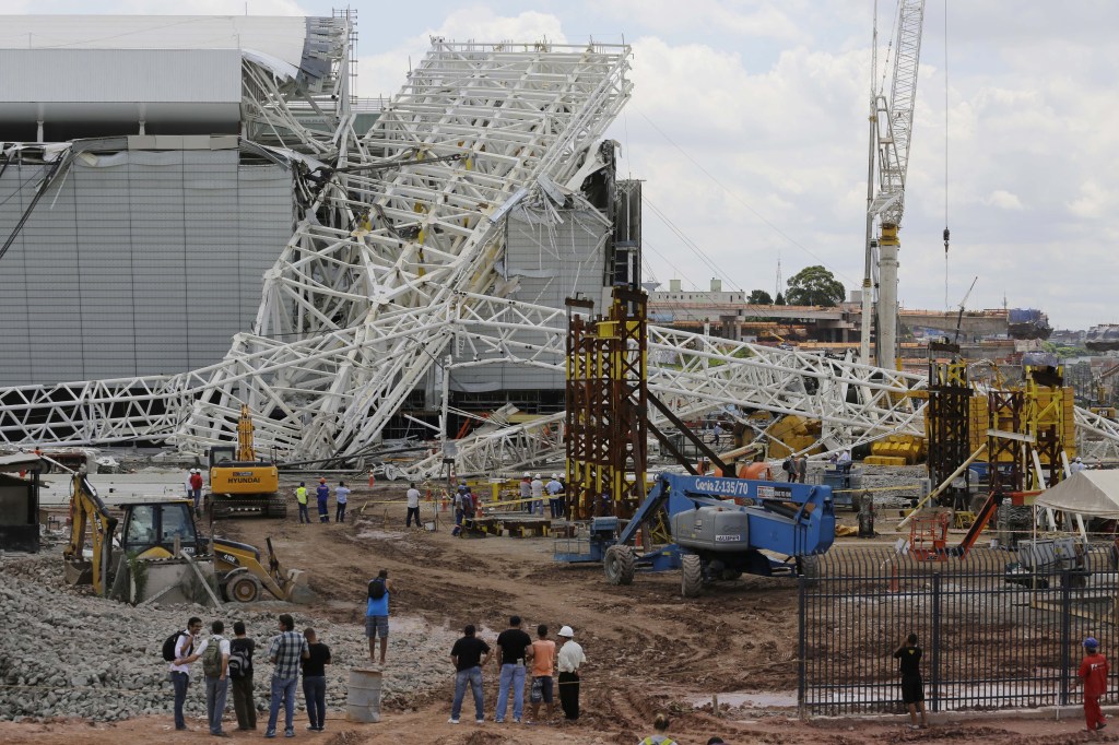 People stand in front of a metal structure that buckled on part of the Itaquerao Stadium in Sao Paulo, Brazil, on Wednesday.