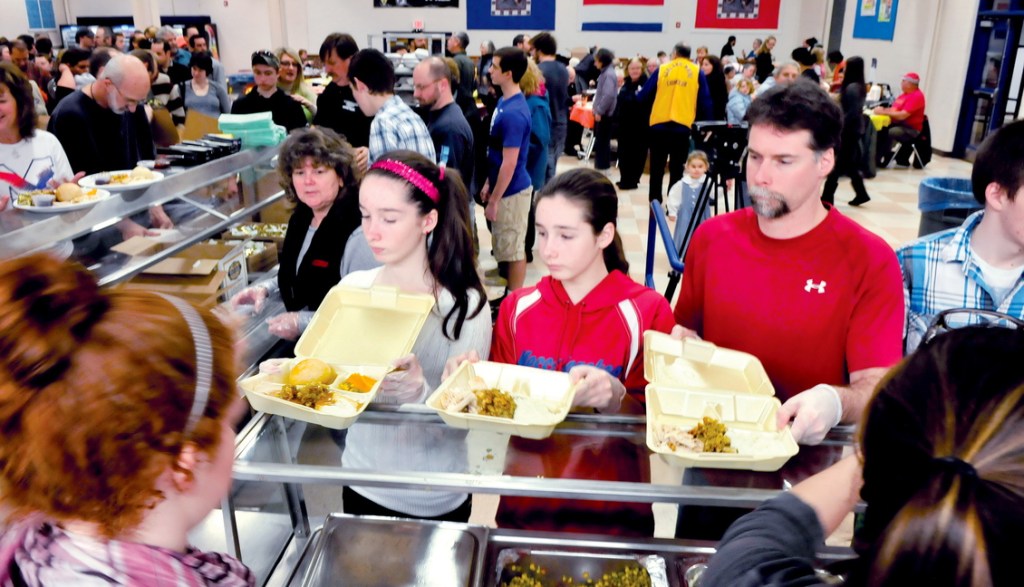 HELPING OTHERS: The Vigue family pitched in to serve dinners during the 24rd annual Messalonskee Thanksgiving Day Community Meal in Oakland today. In photo from left Julia, Kaitlyn and father Jeremy Vigue fill plates of food from volunteers for the hundreds of area folks who ate and mingled with other diners.