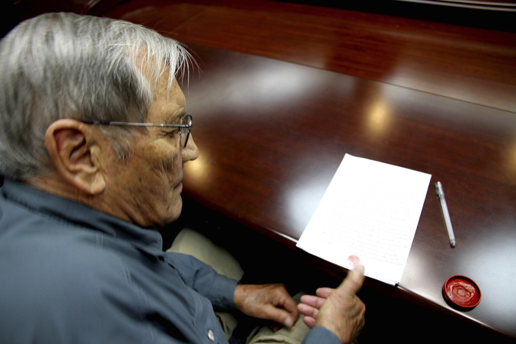 In this Nov. 9, 2013 photo released by the Korean Central News Agency (KCNA) and distributed Nov. 30, 2013 by the Korea News Service, U.S. citizen Merrill Newman, 85, applies his thumb print to a document which North Korean authorities say was an apology which Newman wrote and read in North Korea. Newman, an avid traveler and retired finance executive, was taken off a plane Oct. 26 by North Korean authorities while preparing to leave the country after a 10-day tour.