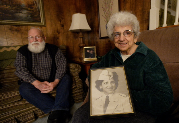 Pauline Young, a combat nurse in World War II and Korea, holds a photograph of herself in her dress uniform in 1942. To the left is friend and fellow veteran John Ames.