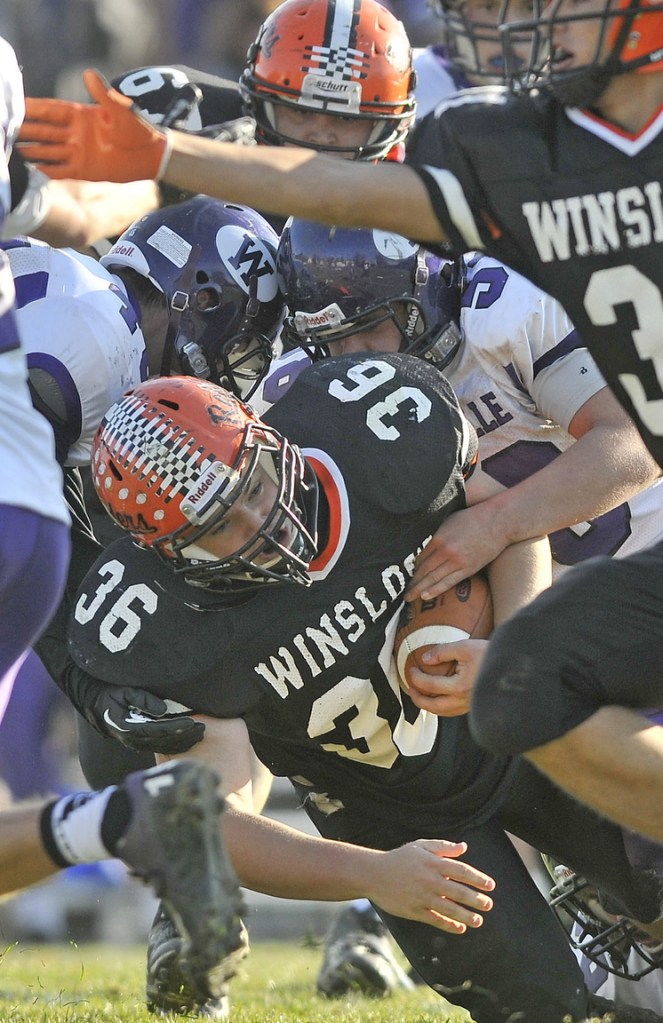 Staff photo by Michael G. Seamans Winslow High School running back Zach Guptill, 36, is tackled by Waterville Senior High School defenders in the second quarter in Winslow on Saturday. Winslow defeated Waterville 49-12.