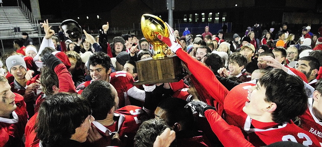 CHAMPS: Cony Rams players and their fans celebrate with gold ball trophy after beating Kennebunk to win the state class B football championship game on Friday in Orono.
