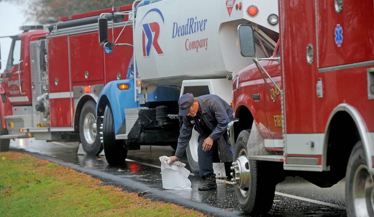 Shawn Mullen, 46, a delivery driver for Dead River Oil, mops up spilled fuel in front of 256 Belgrade Road in Oakland on Friday. The delivery truck apparently spilled small amounts of oil for about six miles in Oakland while making deliveries, according to a town fire official.