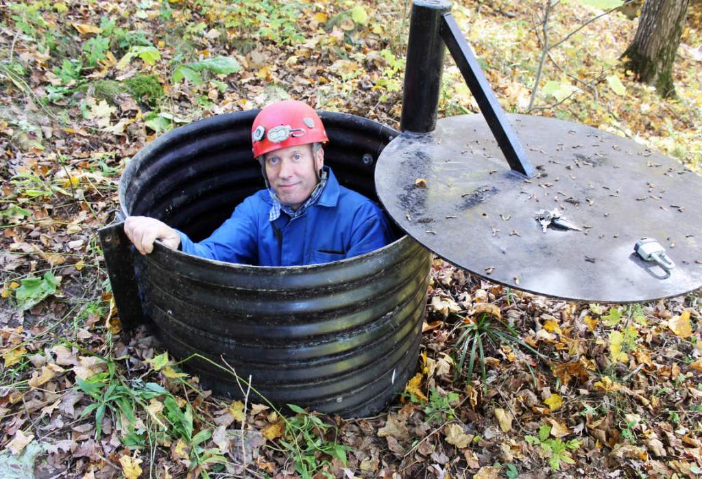 John Ackerman poses in a shaft entrance to his Temple of Doom, one of the 37 caves on his property near Spring Valley, Minn. Associated Press