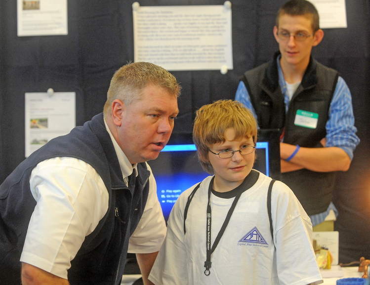 good talk: Peter Gagnon, director of the Capital Area Technical Center in Augusta, speaks with Bodhi Shaw, 12, of Bingham during a Kennebec Valley area high school expo at Thomas College in Waterville on Friday. The schools invited legislators, the governor and other state officials because they want to counteract negative rhetoric about public schools.