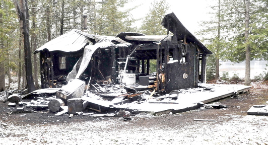 GONE: The contrast between the snow and blackened remains of a camp can be seen on Sunday on the Ironbound Pond Road in Solon after fire destroyed the home on Saturday.