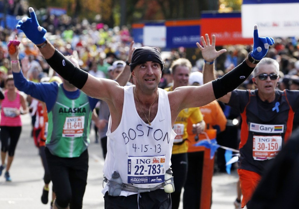 Wearing a shirt that pays tribute to victims of the Boston Marathon bombings, Andrew Mangone of the United States reacts crossing the finish line after completing the New York City Marathon, Sunday, Nov. 3, 2013, in New York.