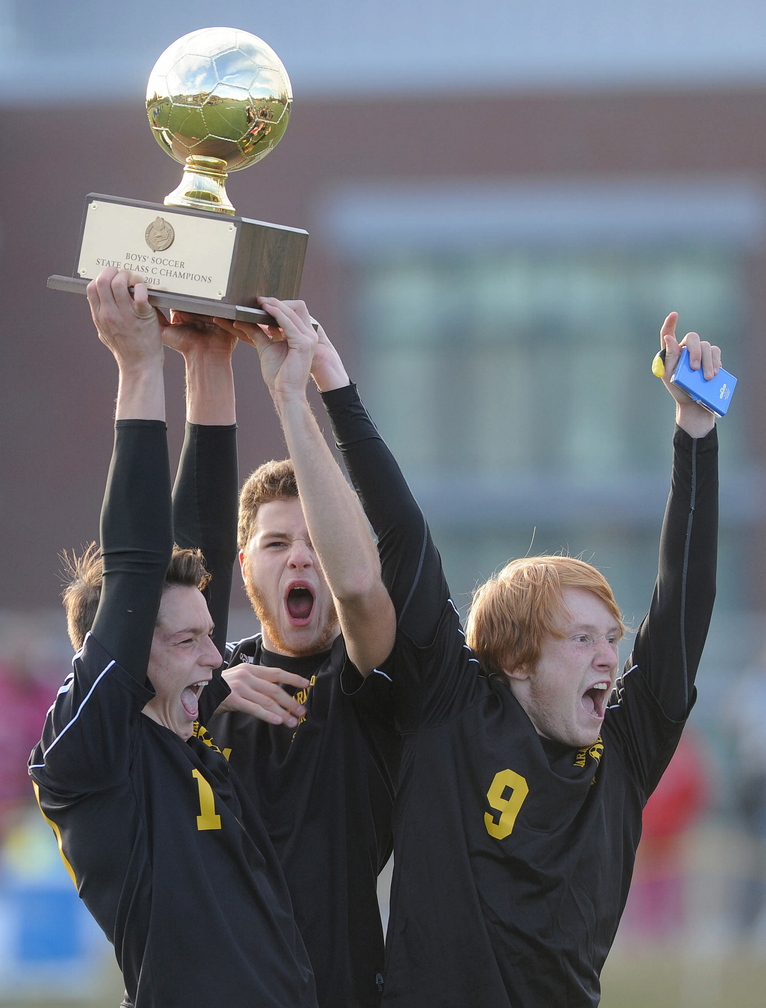 CELEBRATE: Maranacook High School captains Nick LaCasse, 10, Taylor Wilbur, 11, and Alex Tooth, 9, celebrate after receiving the state champion trophy in the Class C State Championship game at Hampden Academy on Saturday. Maranacook defatted Madawaska 2-0.