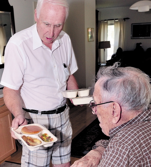 HELPING: Meals on Wheels driver Gil Pelletier, left, delivers food to Thaddy Gondela in Waterville in 2011. The program run by Spectum Generations is one of several area programs facing federal cuts, but helps prevents medical costs because volunteers might recognize a medical issue before it becomes a costly crisis.