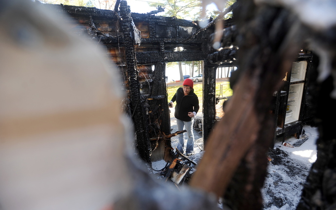 FIRE AFTERMATH: Laura Ellis investigates the damage to the camper trailer she was staying in on Beach Road in South China on Tuesday morning.