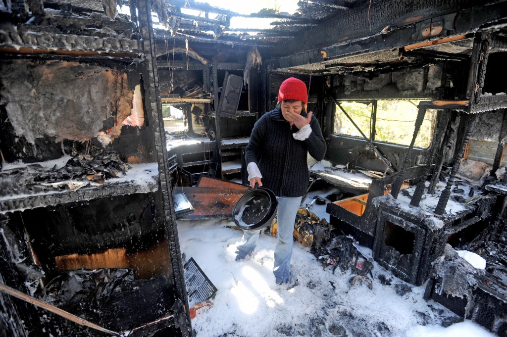 FIRE AFTERMATH: Laura Ellis investigates the damage to the camper trailer she was staying in on Beach Road in South China on Tuesday morning.