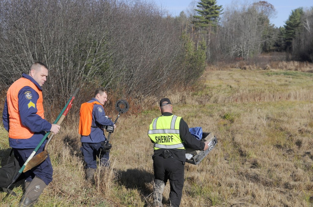 EXCAVATION: Kennebec County Sheriff’s Major Ryan Reardon, right, carries evidence collection tools as State Police Detective Terry James, center, lugs a metal detector while State Police Detective Sgt. Jason Richards carries hand tools into the woods of Manchester on Saturday afternoon to excavate skeletal remains discovered by hunters earlier in the day. The Sheriff’s Department was called just after 8 a.m. when a deer hunter encountered the bones half a mile up a dirt logging road from the Puddledock Road, according to Reardon.