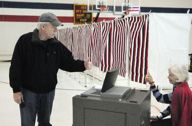 Voter Steve Clarkin, left, and Ward Clerk Louise Lerley exchange thumbs up after the voting machine beeped to show it accepted Clarkin’s ballot on Tuesday at the Augusta Ward 1 polling place in the Augusta Armory. The city has new voting machines that will alert a voter if there is a problem with their ballot and give them the option to fix it.
