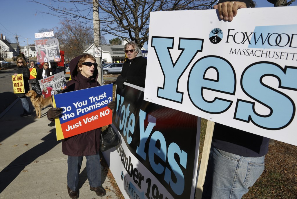 Barbara Morganelli, of Milford, Mass., center left, displays a placard while speaking with Chris Murphy, hand only at right, outside a polling place Tuesday, Nov. 19, 2013, in Milford.