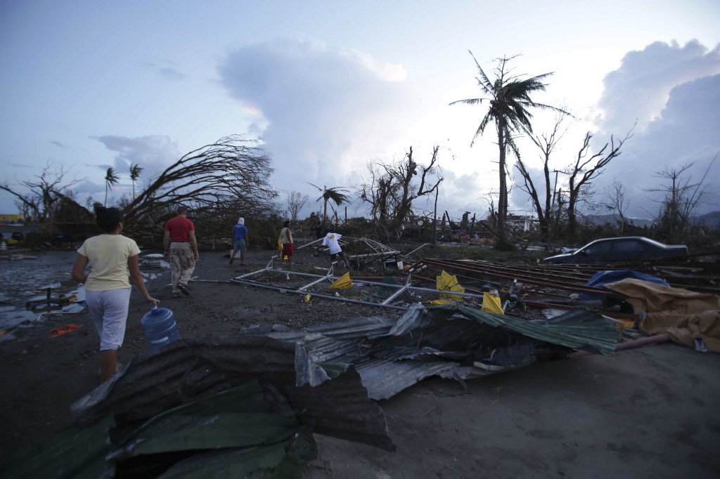 Residents walk by debris after powerful Typhoon Haiyan slammed into Tacloban city, Leyte province, central Philippines on Saturday, Nov. 9, 2013. The central Philippine city of Tacloban was in ruins Saturday, a day after being ravaged by one of the strongest typhoons on record, as horrified residents spoke of storm surges as high as trees and authorities said they were expecting a “very high number of fatalities.”