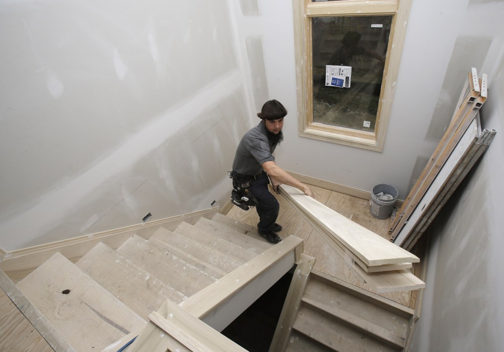 Will Hostetler, a carpenter with Larry Block Builders, carries trim downstairs at a new residential building under construction, in Pepper Pike, Ohio. Construction of single-family homes could slow in the coming months, but construction of apartments has increased.