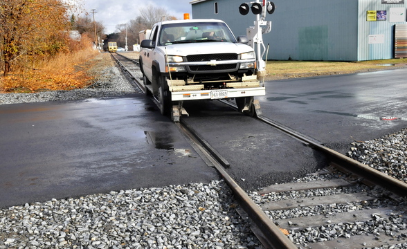 GENTLE CROSSING: A specially equipped truck rides on top of the rails of the Pan Am Railway over the recently improved crossing on Summit Street in Fairfield on Monday.