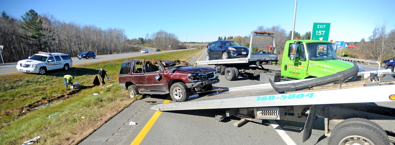 Clean-up: Officials pick up debris as two cars involved in a roll-over accident are loaded onto trucks at the scene of two-car accident on southbound Interstate 95 in Palmyra on Monday.