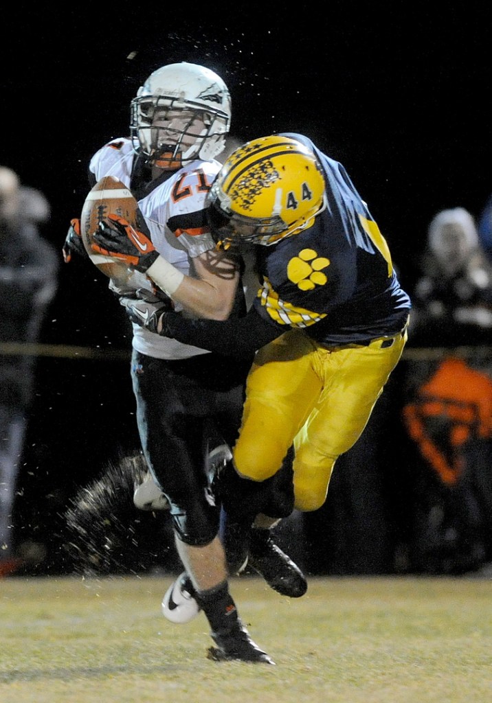 Staff photo by Michael G. Seamans Skowhegan Area High School's Ben Salley, 21, makes a catch as he is hit by Mt. Blue High School defender Nathan Pratt-Holt, 44, in the second quarter in Farmington on Saturday.