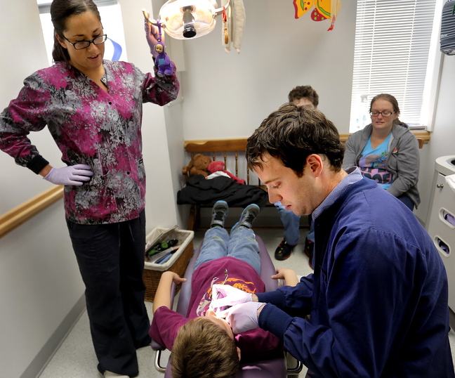 Dr. Michael Dowling works on patient Aiden Serber, 8, of Westbrook, as dental hygienist Trisha Drewry assists Wednesday at Falmouth Pediatric Dentistry. Dowling says new MaineCare audits carry excessive fines for small errors and the state has the ability to make the audits more fair.
