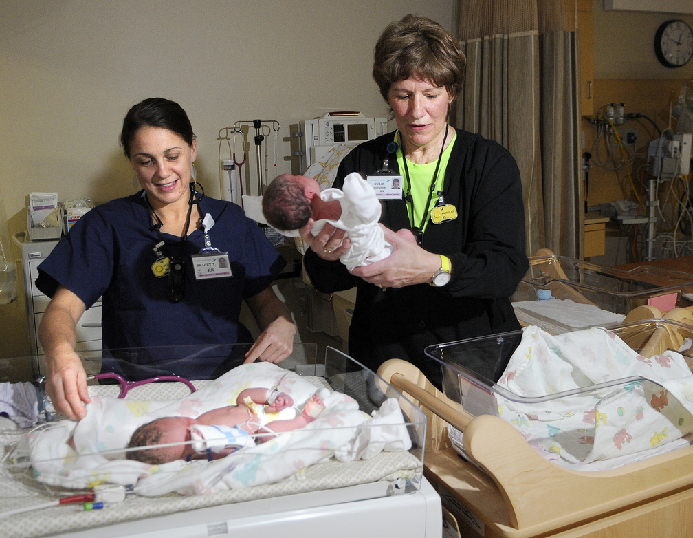 DELIVERING: Nurse Julie Smithson, right, lifts day old infant Hannah Veilleux away from her twin, Samuel, attended by nurse Tracey Thornton, at MaineGeneral’s new neonatal intensive care unit in Augusta on Sunday. The siblings, born five weeks early, were the first babies born at the new hospital.