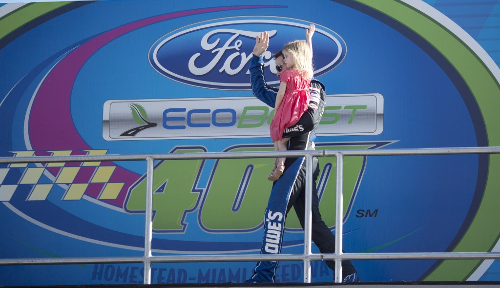 Jimmie Johnson holds his daughter, Genevieve, as he greets fans during driver introductions before the NASCAR Sprint Cub Series auto race in Homestead, Fla., Sunday, Nov. 17, 2013.