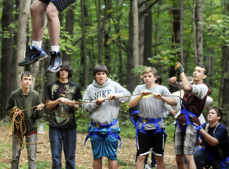 COMING DOWN: Cony High School students help a classmate descend from the catwalk at the school’s rope course in Augusta. The physical education class emphasizes cooperation instead of competition.