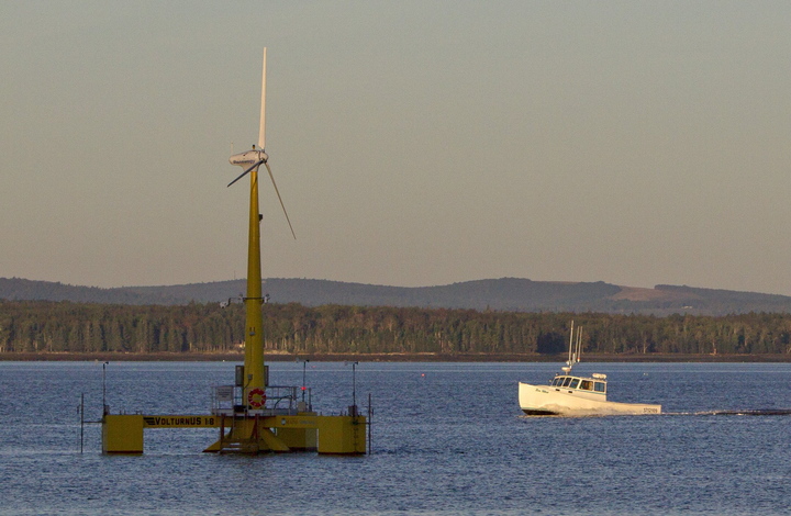 A lobster boat passes the country’s first floating wind turbine, off the coast of Castine, in September.