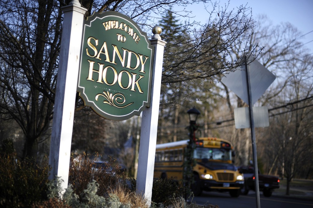 A bus drives past a sign reading Welcome to Sandy Hook, Wednesday, Dec. 4, 2013, in Newtown, Conn. The 911 calls from the Sandy Hook Elementary School shootings released Wednesday show town dispatchers urged panicked callers to take cover, mobilized help and asked about the welfare of the children as the boom of gunfire could be heard at times in the background. The recordings are released under court order after a legal challenge from The Associated Press.
