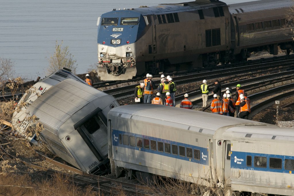 An Amtrak train, top, traveling on an unaffected track, passes a derailed Metro-North commuter train in the Bronx borough of New York on Dec. 1. Two federal lawmakers proposed Sunday that trains nationwide be outfitted with cameras pointed at engineers and at the tracks.