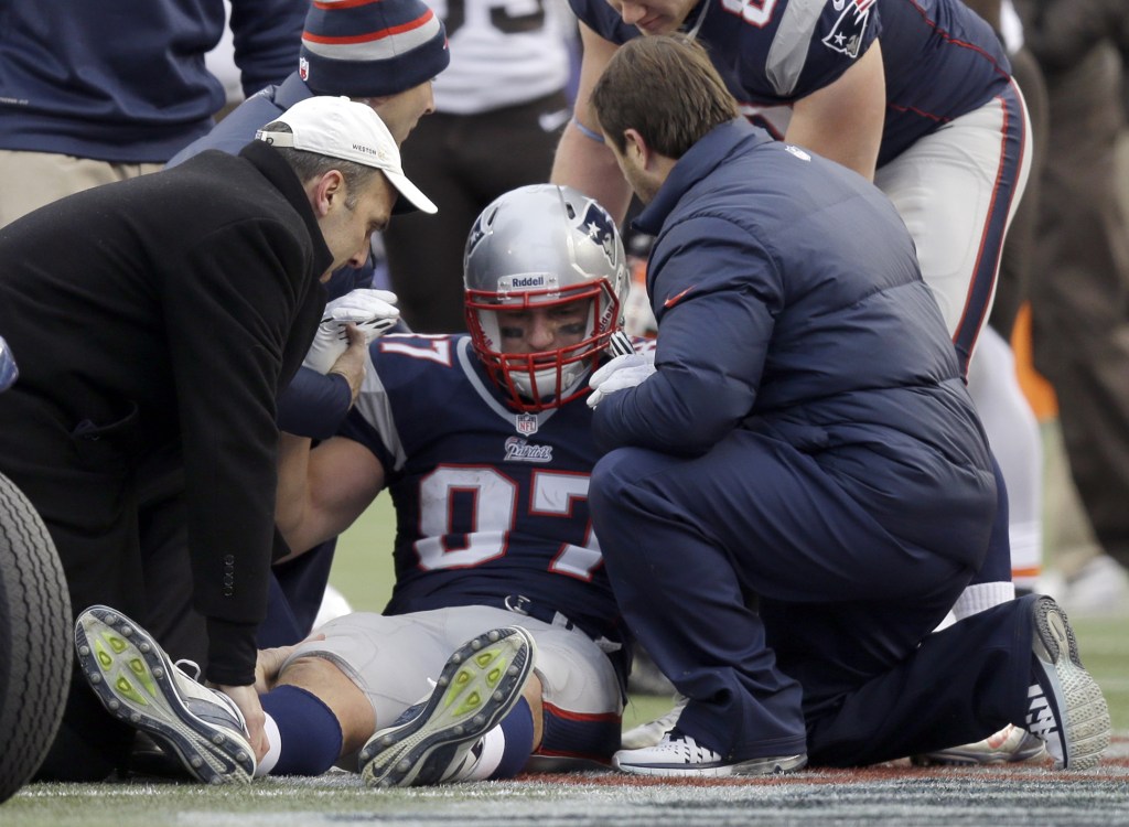 New England Patriots tight end Rob Gronkowski, center, is helped after being injured following a catch against the Cleveland Browns in the third quarter of an NFL football game on Sunday, Dec. 8, 2013, in Foxborough, Mass. (AP Photo/Steven Senne)