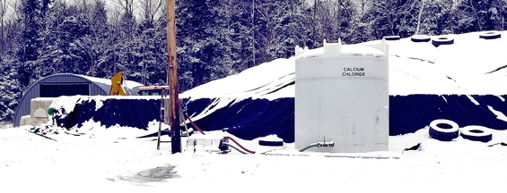 Equipment: A large tank of calcium chloride stands in front of the sand pile at Ellis Construction in Farmingdale.