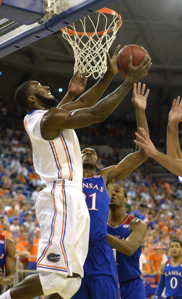 Florida’s Patric Young evades the block of Joel Embiid during the first half of the Gators’ 67-61 win over visiting Kansas Tuesday.