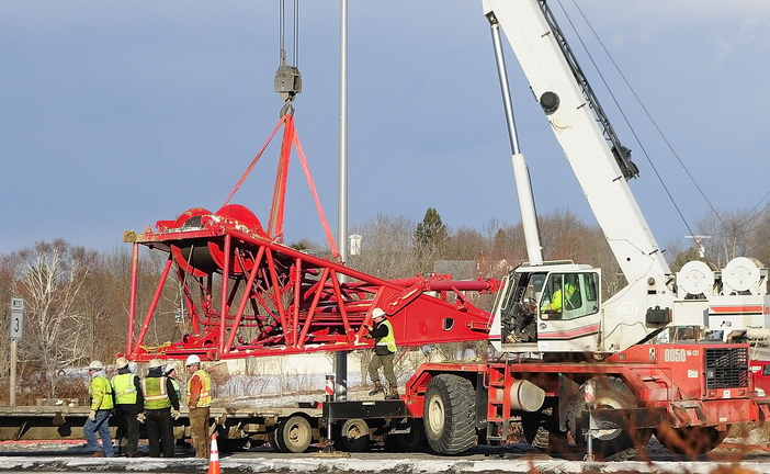 Needs a Lift: Workers use a tow truck to retrieve a crane section Wednesday at the intersection of U.S. Route 201 and Route 3 in Augusta. It had fallen off a tractor-trailer earlier in the day while the tractor-trailer was turning off U.S. Route 201 toward the Cushnoc Crossing bridge on Route 3.