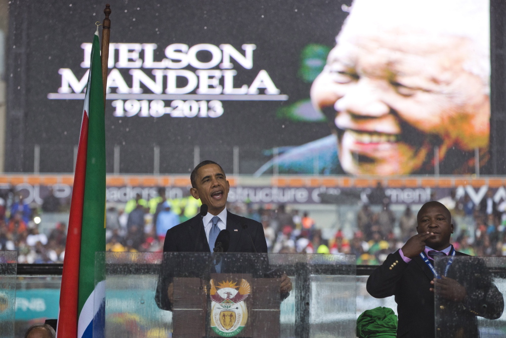 President Barack Obama delivers his speech next to a sign language interpreter during a memorial service at FNB Stadium in honor of Nelson Mandela on Tuesday in Soweto. The national director of the Deaf Federation of South Africa says the interpreter was a “fake.”