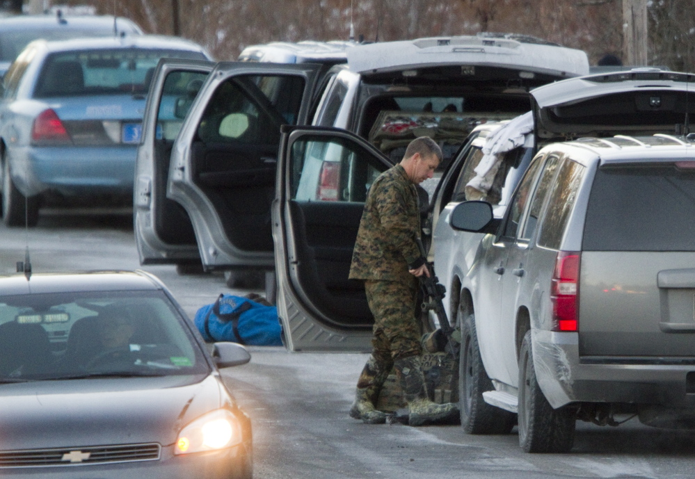 Carl D. Walsh/Staff Photographer A police officer wearing camouflage gear puts away his rifle after a standoff ended in a fatal shooting on Route 35 in Hollis on Thursday. Police said John Knudsen was alone in his home when he shot at troopers, eliciting return fire.