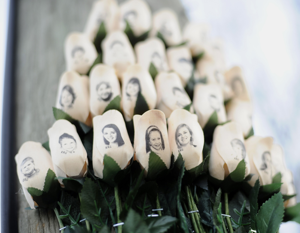(File) White roses bearing the faces of victims of the Sandy Hook Elementary School shooting are displayed on a telephone pole near the school in Newtown, Conn. Adam Lanza opened fire inside the Sandy Hook Elementary School on Friday, Dec. 14, 2012, in Newtown, killing 26 students and educators.