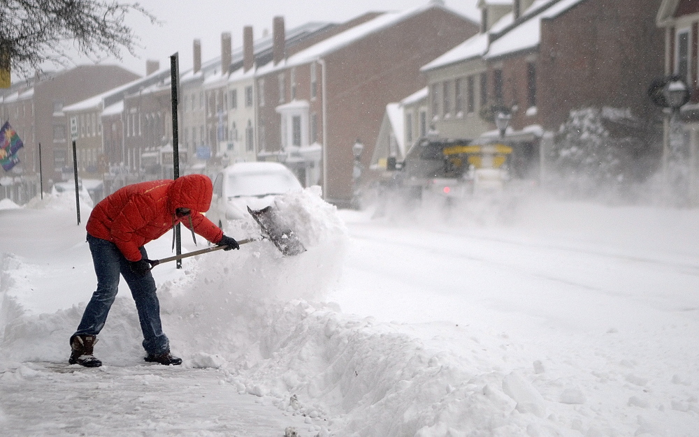 CLEAN UP: Nathan Sennett shovels snow off the sidewalk in front of his business, Lux, on Sunday in Hallowell.