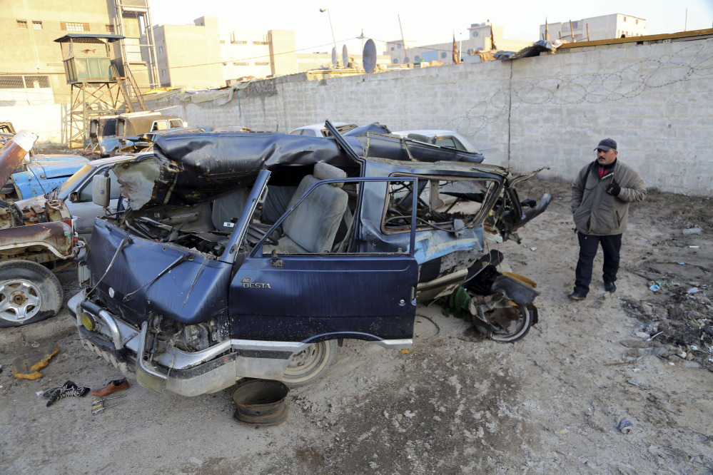 The Associated Press An Iraqi man inspects damaged vehicles in a car bomb attack in Baghdad, Iraq, Monday, Dec. 16, 2013. Iraqi officials say bombings in and around Baghdad have killed and wounded tens of people.