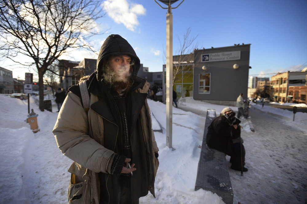 Matt Coffey, who is homeless, stays bundled up in Monday’s cold as he smokes outside the Preble Street Resource Center in Portland. Coffey says he usually sleeps outside at night even when it’s bitter cold, staying warm enough using his survival skills.