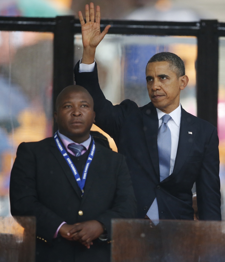 President Barack Obama waves standing next to the sign language interpreter after making his speech at the memorial service for former South African president Nelson Mandela at the FNB Stadium. South Africa’s deaf federation said on Wednesday that the interpreter on stage for Mandela memorial was a ‘fake’.