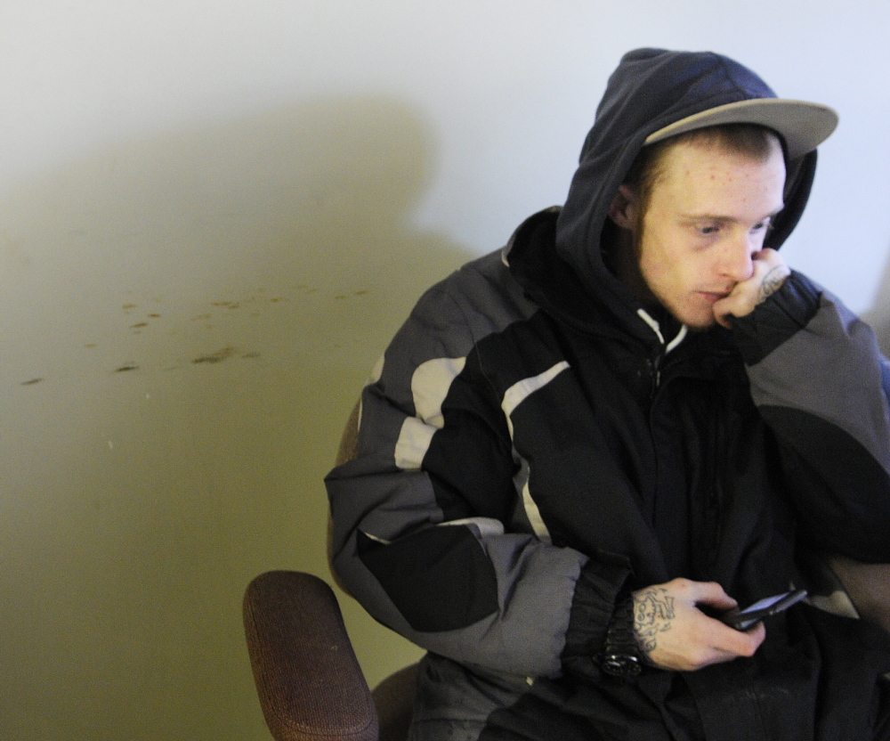 SHELTER: Adrien Patenaude, 23, texts for a ride to the homeless shelter in Waterville while taking a break from the elements Monday at the warming center on Front Street in Augusta. The Center opened for the winter and Patenaude, who is homeless, spent much of the day there while searching for a bed.