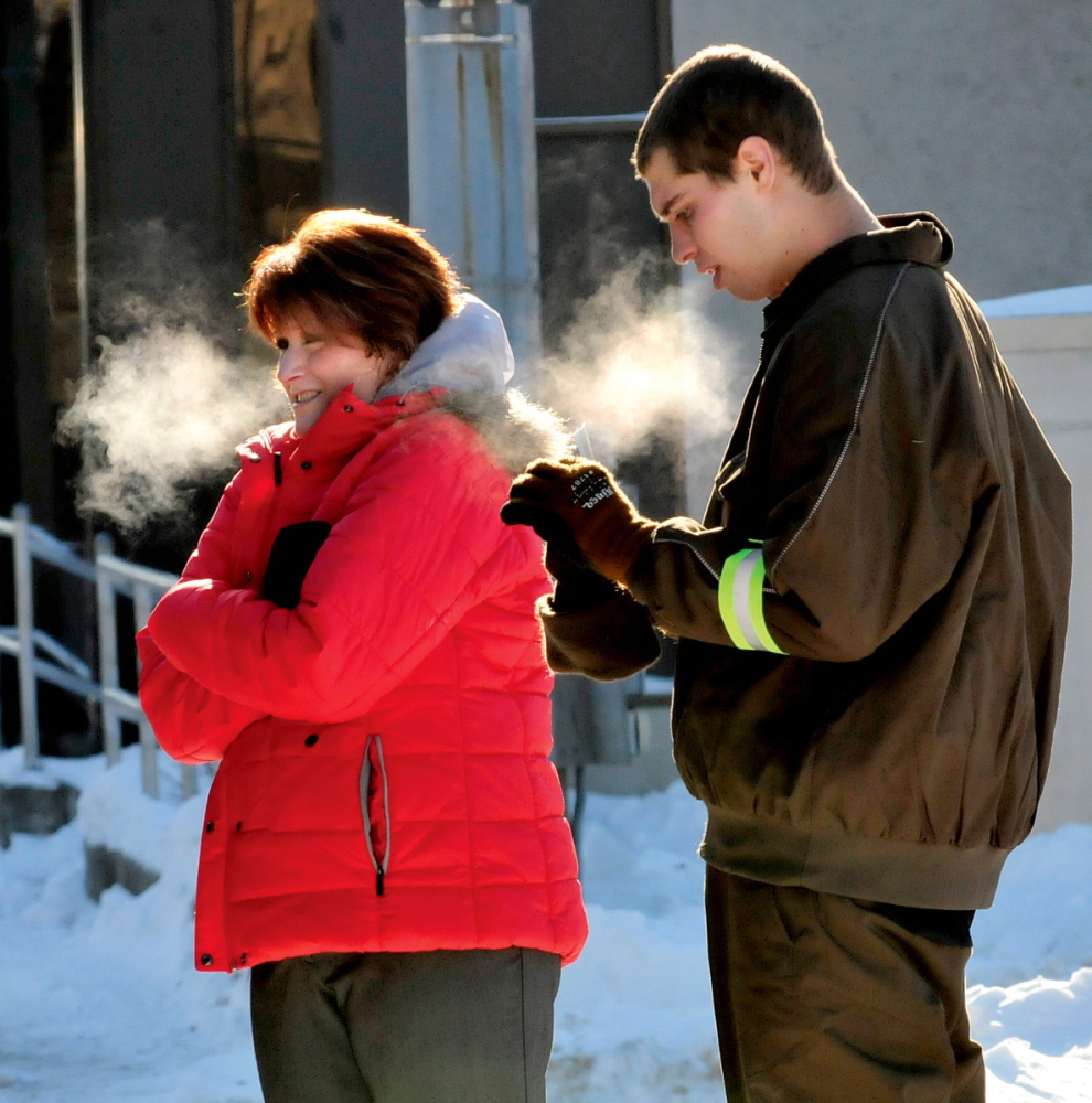 COLD RUSH: Warm breath turned to cold vapor as Laurie Laliberte and delivery driver Peter Schultz waited outside to receive packages from a United Parcel Service truck on a frigid day in Waterville on Tuesday.
