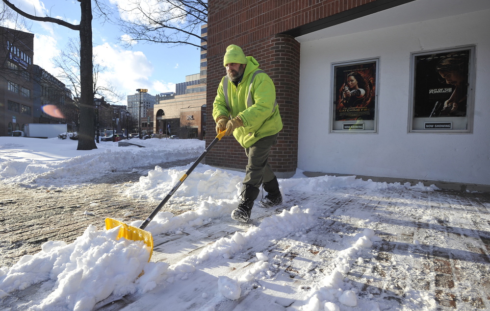 Ron Langway of Portland cleans snow from the sidewalks around the Nickelodeon movie theater Monday. Langway works for the management company that owns the building. More snow is expected Tuesday.