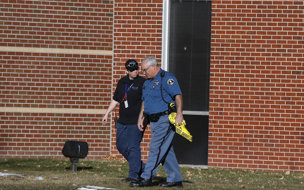 A security officer and a sheriff’s deputy walk together, three days after a shooting attack at Arapahoe High School in Centennial, Colo., Monday, Dec. 16, 2013. During the attack, the shooter shot a classmate in the head at close range with a shotgun, before killing himself.